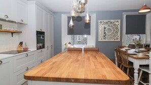 A modern kitchen with a central island, white cabinetry, and pendant lighting. - The Wonky Nest (Windermere)