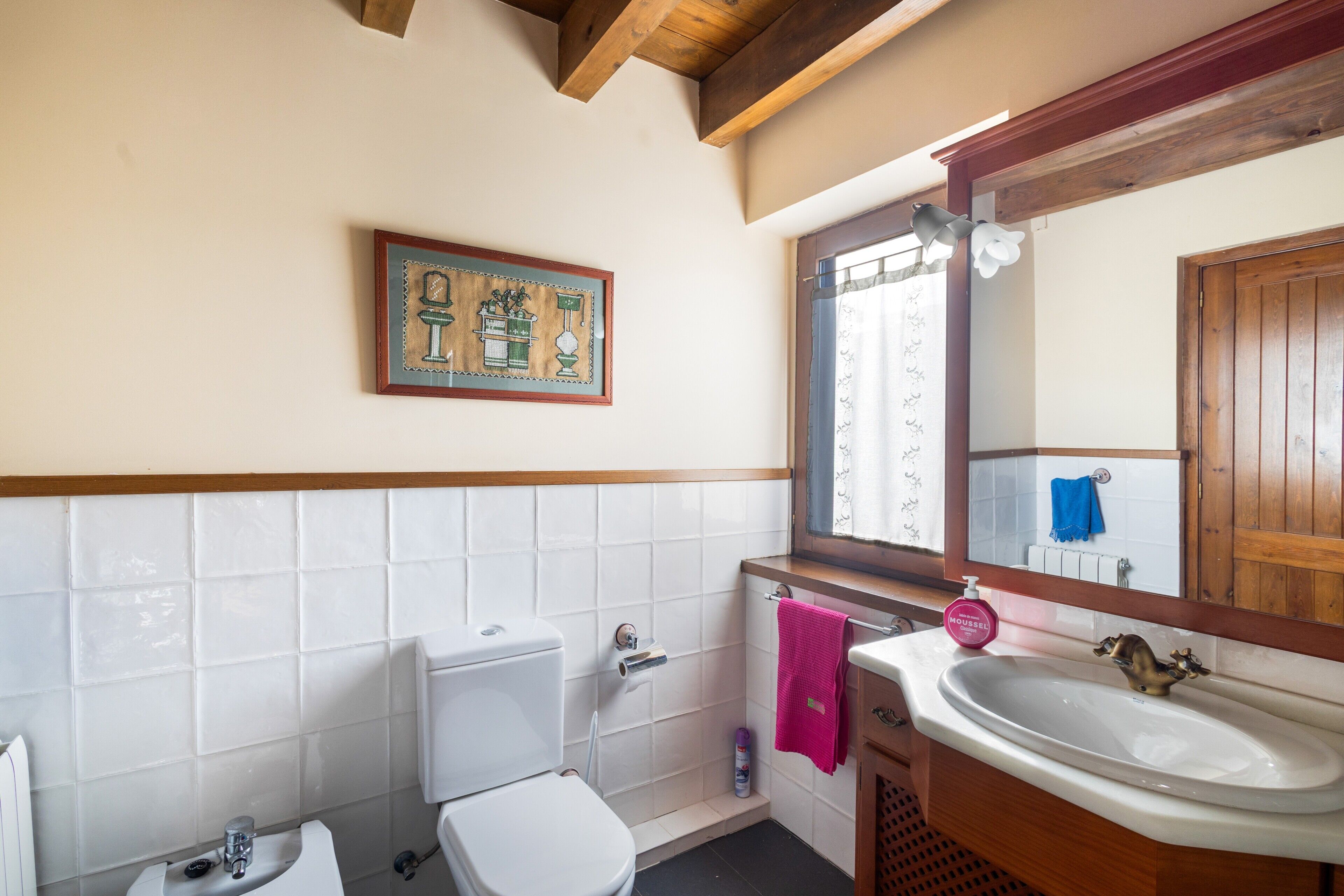 A bathroom with a toilet, sink, and window.