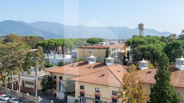 A residential area with terracotta-tiled roofs, a water tower, and a clear view of distant mountains. - Homiday - Jasmine One Min[Hospital][Airport-Free Parking] (Pisa)