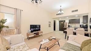 Una sala de estar moderna con televisor, sofá, mesa de centro y comedor.