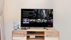 Un mueble moderno de entretenimiento con un televisor de pantalla plana mostrando la interfaz de Netflix.