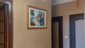 A hallway with a wooden table, a painting, and a chandelier.