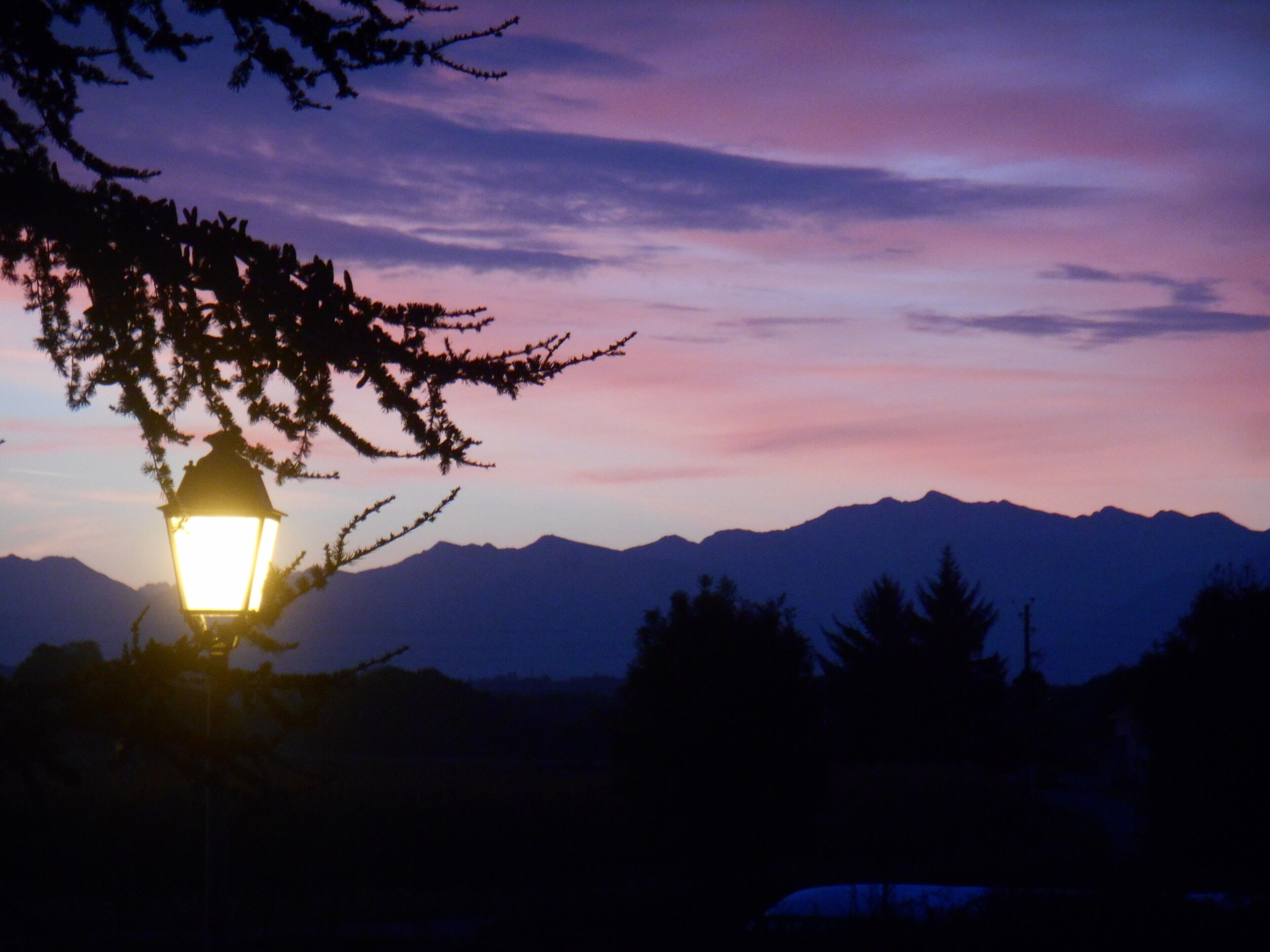 Paisaje montañoso al atardecer con un farol en primer plano.