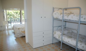 A dormitory room with bunk beds, a wardrobe, and a chair. - Spacious Flat by the Beach (Lignano Sabbiadoro)