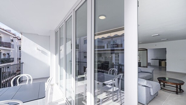 A modern apartment with a balcony, a dining area, and a living room.