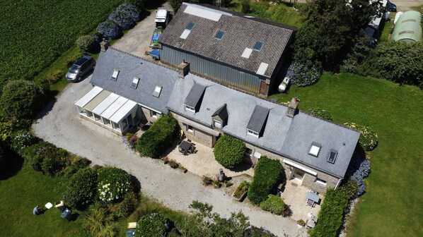 A two-story house with a large patio area, a garage, and a driveway. - GITE AGAPANTHE, Kerguével, Plon-Porzay, near Locronan and beaches. (Plonévez-Porzay)
