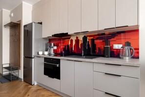 Eine moderne Küche mit einem Edelstahl-Kühlschrank, einem eingebauten Backofen und einer farbenfrohen Spritzschutzwand.