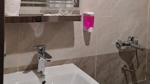 Une salle de bain équipée d’un lavabo, d’un miroir, d’un porte-serviettes et d’une douche.