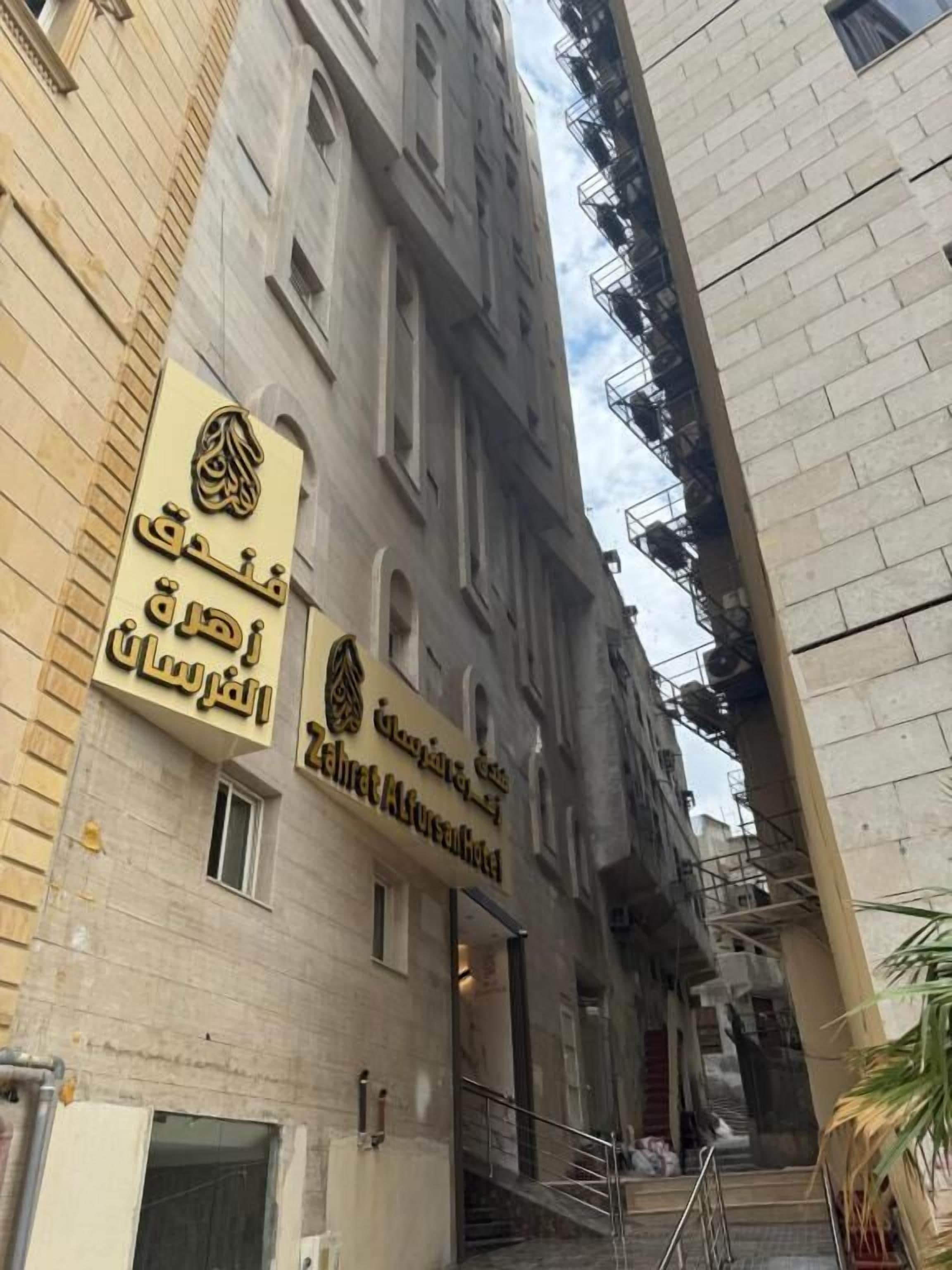 A hotel entrance with a sign in Arabic and English.