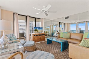Ein geräumiges Wohnzimmer mit Deckenventilator, großem Fenster und Meerblick.
