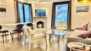 Een moderne woonkamer met een glazen salontafel, een bank en een eethoek met stoelen.
