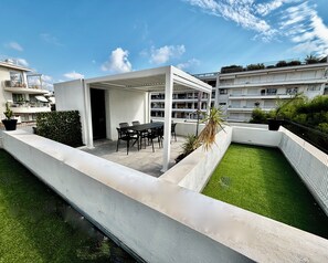 A rooftop terrace with a dining area, a small garden, and a white building structure. - PalmbeeCannes 4à6 personnes 70m2+Terrasses à 200m des Plages, 100m du PalmBeach (Cannes)