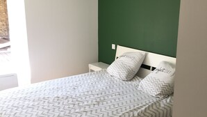 A bedroom with a bed, white nightstands, a green accent wall, and a chevron-patterned bedspread. - Parenthèse nature au cœur des Gorges du Tarn - Charming house & patio (Rivière-sur-Tarn)