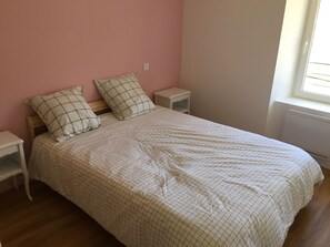Ein Schlafzimmer mit einem Bett, zwei Nachttischen, einem Fenster und einer Heizung.