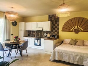 Een ruimtelijke leefruimte met een eethoek, kitchenette en een bed.
