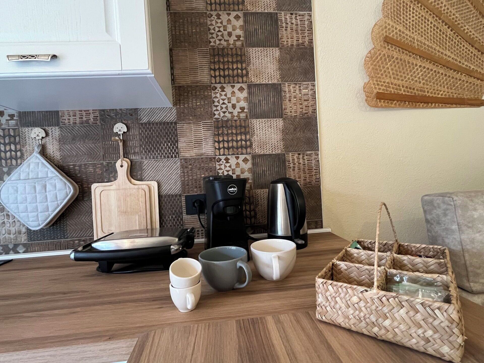 A kitchen with a coffee maker, a kettle, and a cutting board.