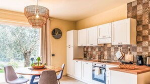 A modern kitchen with white cabinets, a built-in oven, and a dining area with a round table and chairs. - Beautiful apartment for 4 people with A/C, WIFI, patio and panoramic view (Finale Ligure)