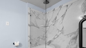 Une salle de bain avec une douche à parois de verre, des murs en marbre et une baignoire.
