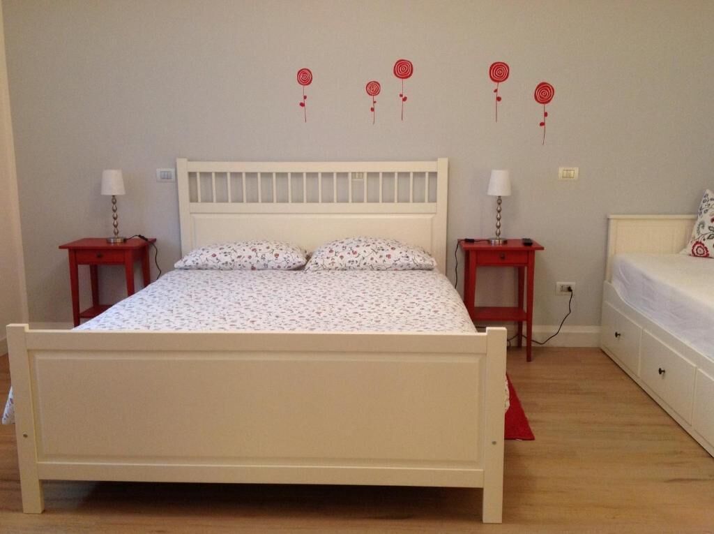 Ein Schlafzimmer mit einem weißen Bett, zwei Nachttischen, einer Kommode und Wanddekorationen.