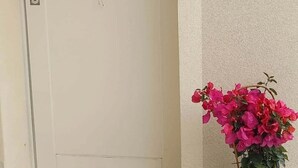 Une porte décorée d’un attrape-rêves et agrémentée d’un bouquet de fleurs roses.