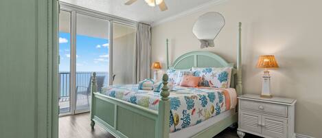 Un dormitorio con cama, mesita de noche, ventilador de techo y vistas al exterior.
