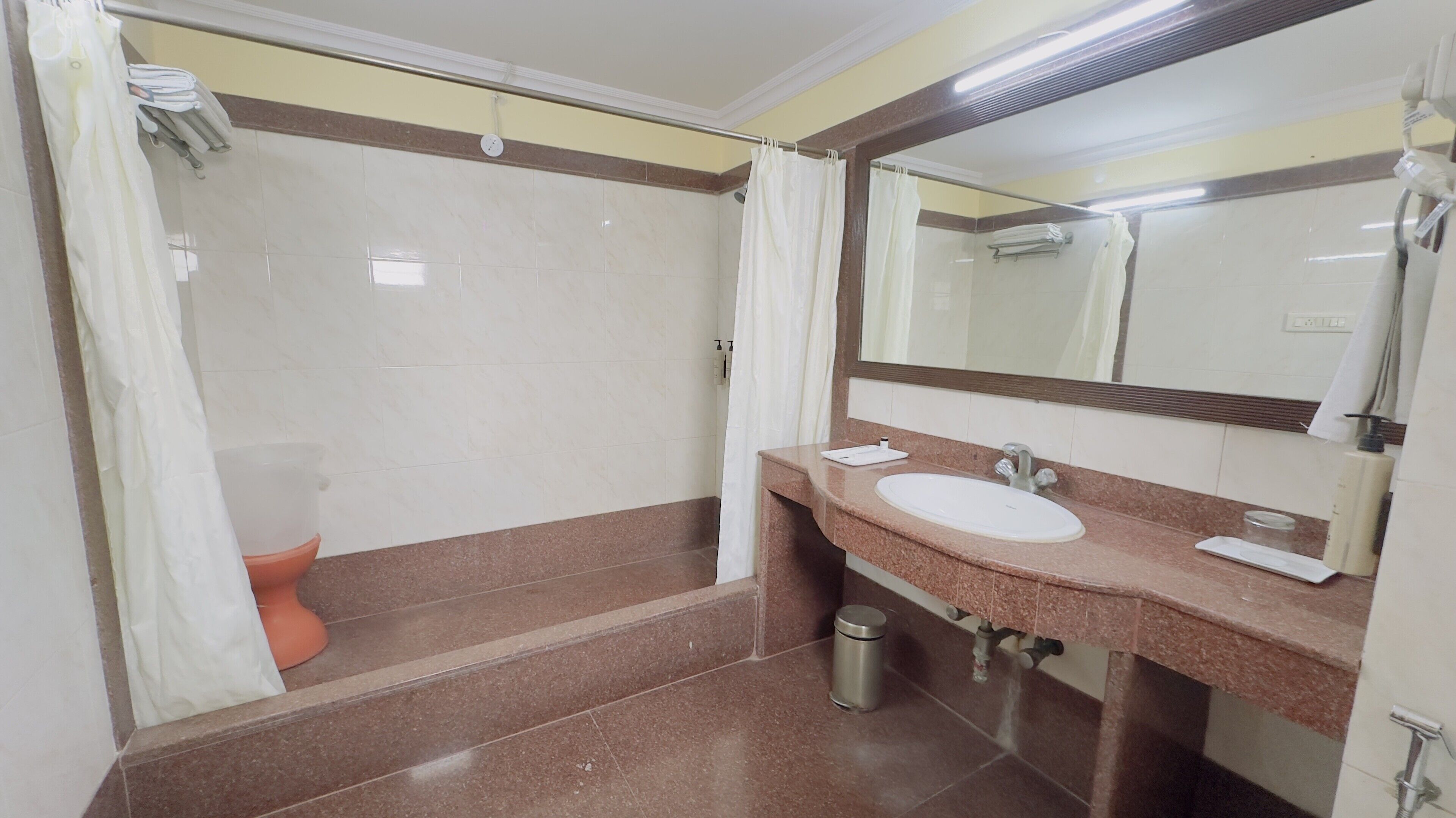 Un baño con ducha, inodoro, lavabo y espejo.