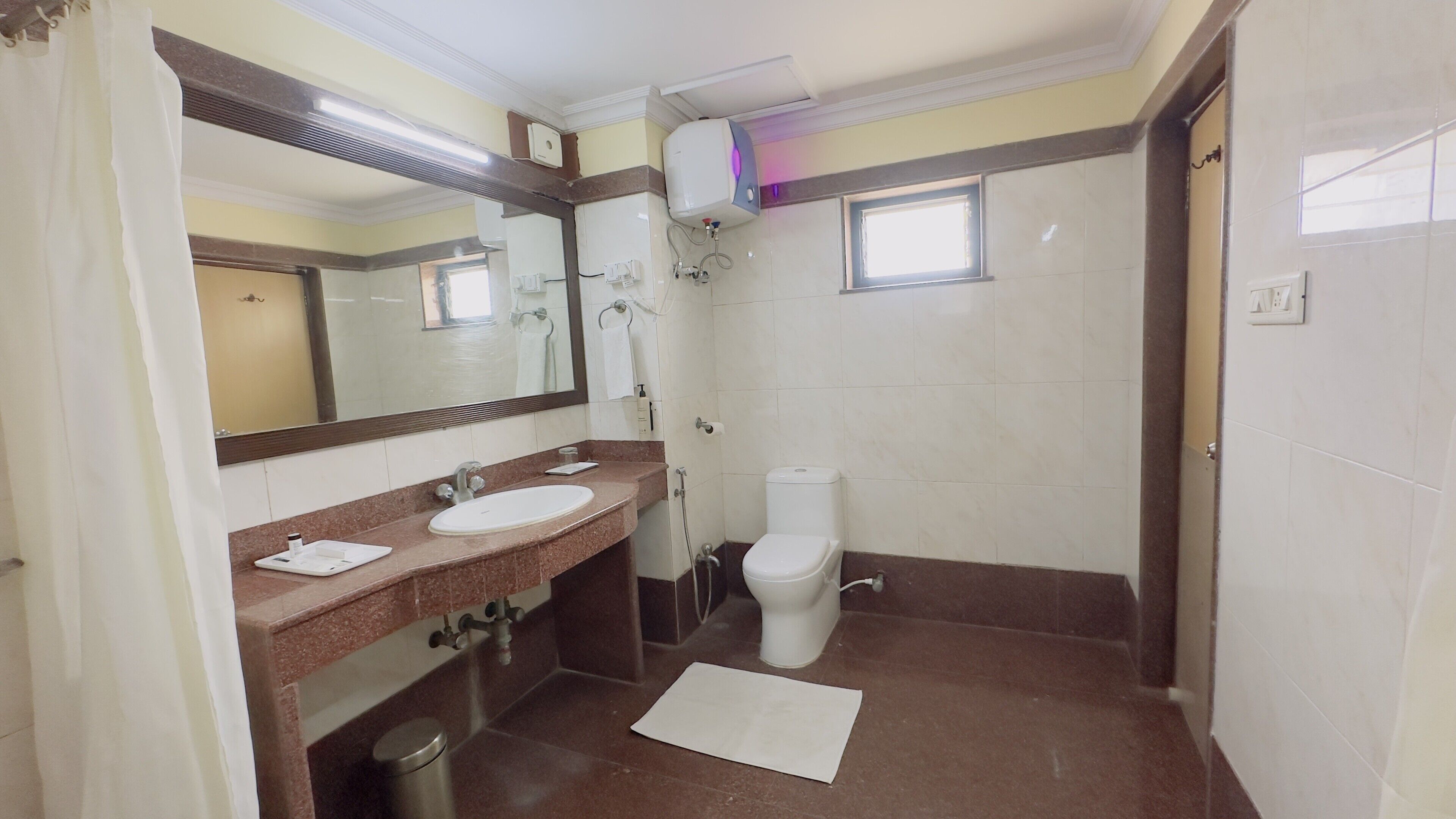 A bathroom with a sink, mirror, toilet, and shower.