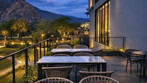 A terrace with outdoor seating, a mountain backdrop, and a building with large windows. - Avisa Hotel & Resort Abu Road - Luxury Pool & Mountain View (Abu Road)