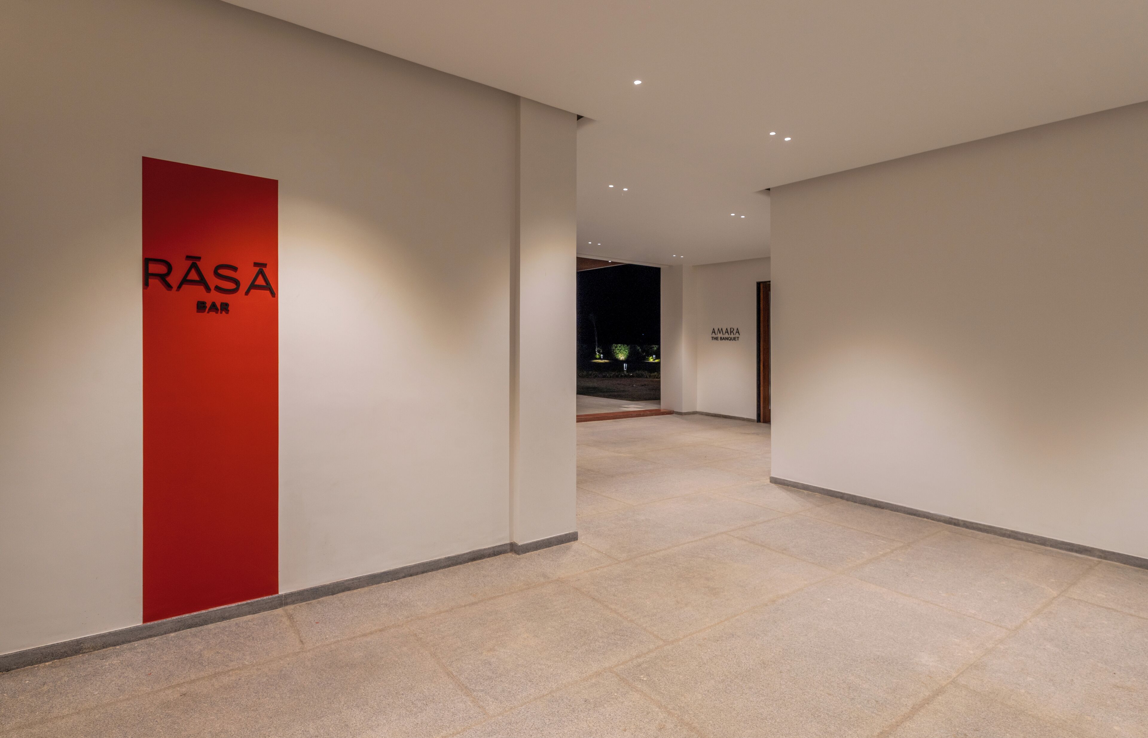 A modern hallway with a red sign for RASA Bar and another sign for Amara The Sanctuary.