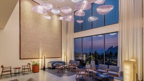 A spacious lobby with modern furniture, large windows offering a city view, and decorative hanging lights. - Avisa Hotel & Resort Abu Road - Luxury Pool & Mountain View (Abu Road)