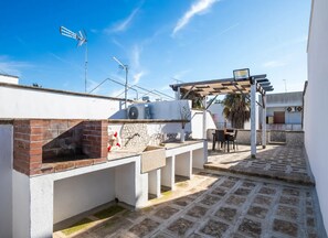 Eine Dachterrasse mit Backofen, Sitzgelegenheiten im Freien und mehreren Antennen.