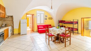 Une cuisine compacte équipée d’un lave-linge, d’une table à manger avec des chaises, d’un canapé rouge et d’un lit superposé.