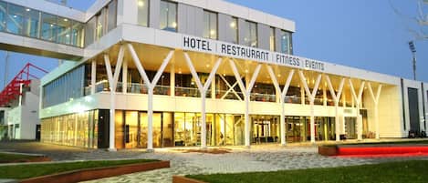 Un hotel moderno con fachada de vidrio, con la leyenda "HOTEL RESTAURANT FITNESS EVENTS".