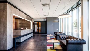 A modern reception area with a reception desk, leather seating, and large windows. - Modern Retreat with Free EV Charging, and On-Site Restaurant Near Autotron (Oss)