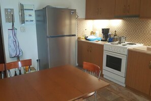 Eine Küche mit Kühlschrank, Herd und Holzschränken.