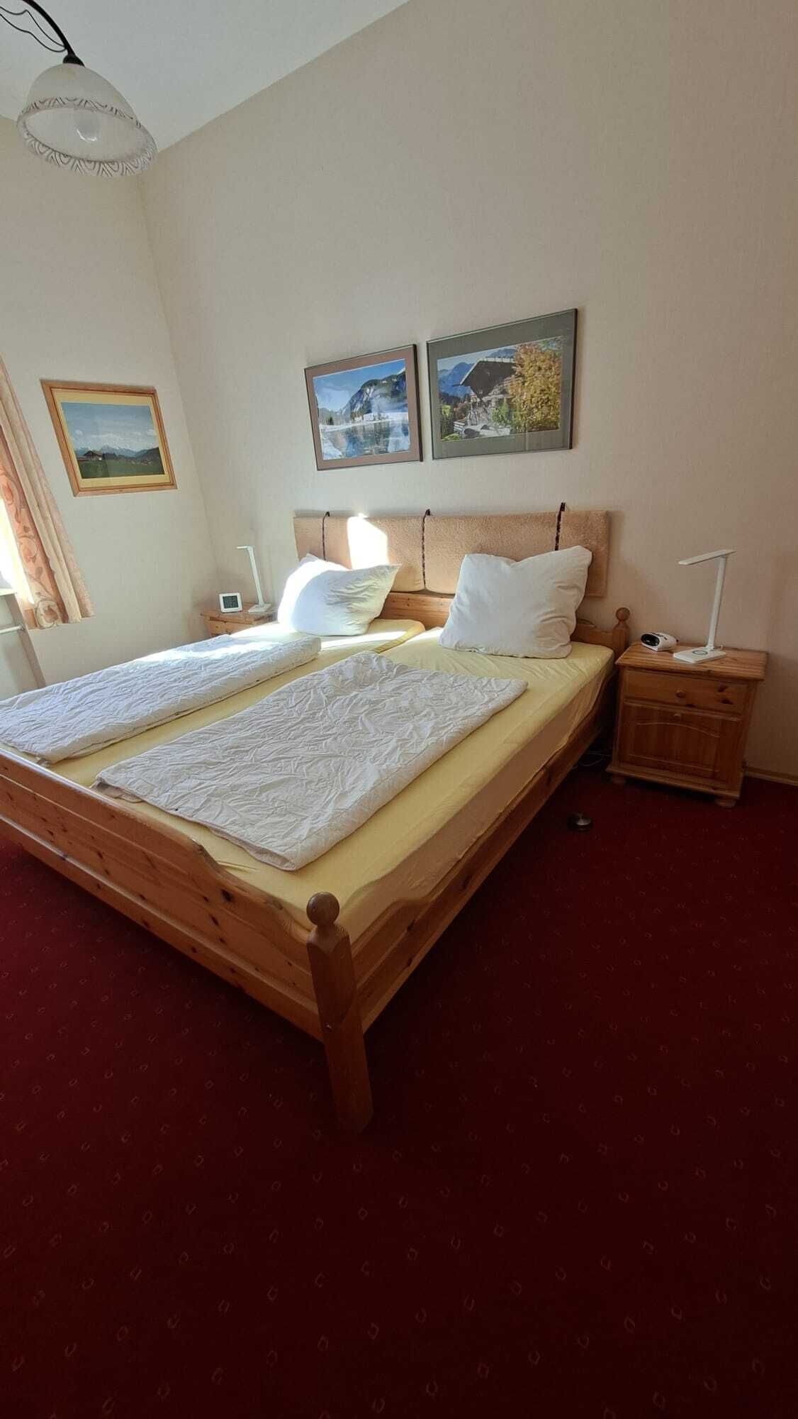 Ein Doppelbett mit Holzrahmen, zwei Nachttische, ein Beistelltisch und zwei Wandbilder.