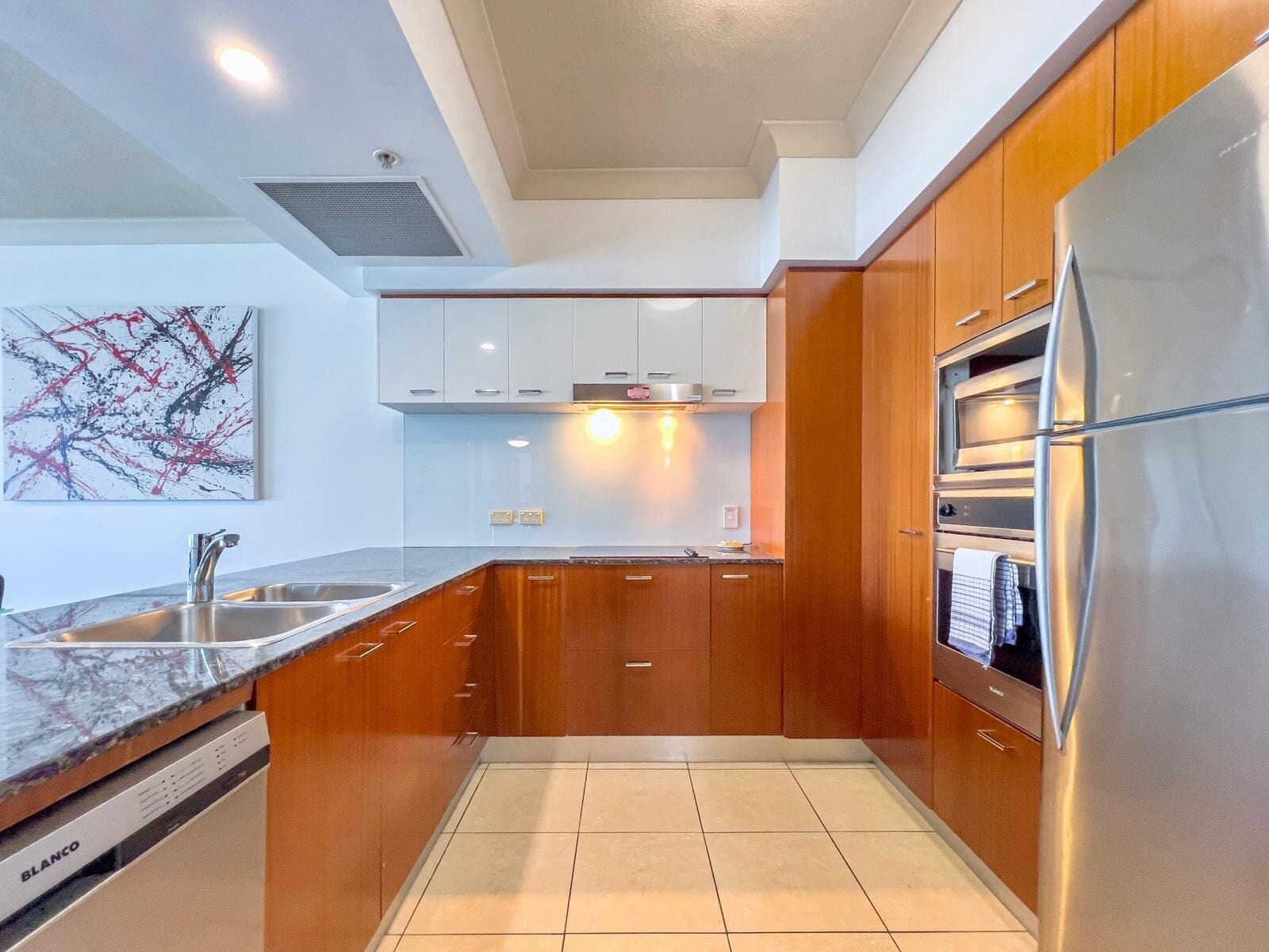 Una cocina moderna con armarios de madera, un refrigerador de acero inoxidable y un lavavajillas.
