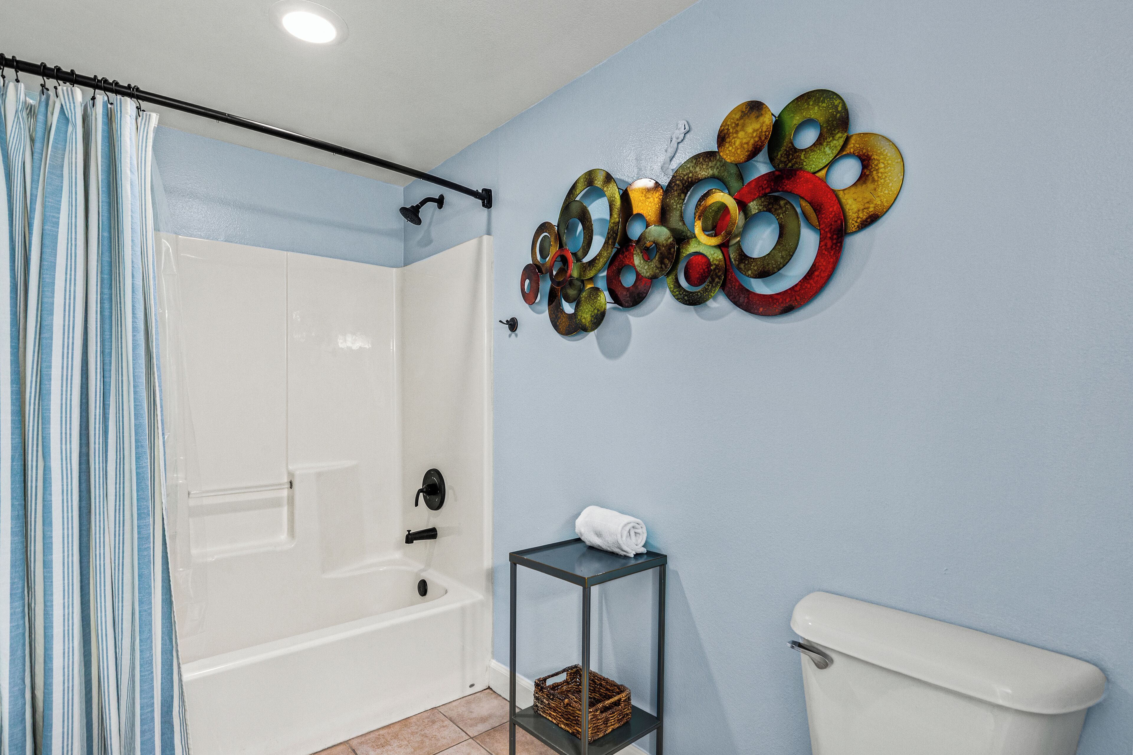 A bathroom with a shower, toilet, and a wall-mounted shelf with a basket.