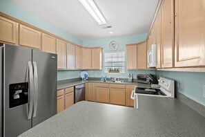 A modern kitchen with wooden cabinets, stainless steel appliances, a built-in oven, and a microwave. - Salt Air Retreat – Family-Friendly Surfside Home with shared pool (Myrtle Beach)