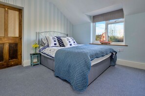 Ein Schlafzimmer mit Bett, einem Fenster mit Aussicht und einem kleinen Tisch mit Blumen.