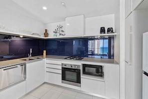 A modern kitchen with a gas stove, oven, microwave, and dishwasher. - Circle on Cavill 1174 (Gold Coast)