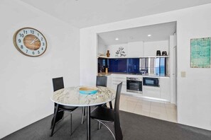 A modern kitchen with white cabinets, a built-in oven, and a microwave. - Circle on Cavill 1174 (Gold Coast)