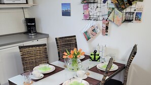 A dining area with a white table, black chairs, and a vase with flowers. - Holiday Apartment Zwischenwasser (Jübek)