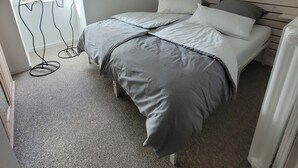 A bedroom with a bed, a painting, a window with blinds, and a ceiling light. - Holiday Apartment Zwischenwasser (Jübek)