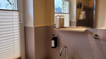 Ein Badezimmer mit Waschbecken, Spiegel und Fenster mit Jalousien.