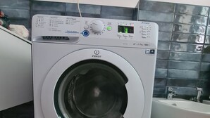 Lavadora de carga frontal con pantalla digital, panel de control y una etiqueta azul que indica una garantía de 5 años.
