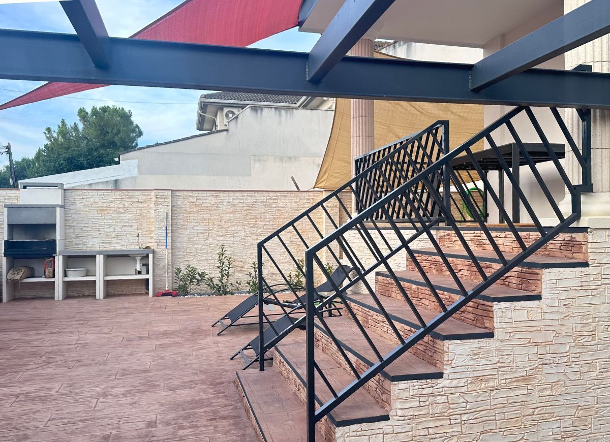 Una escalera con barandilla metálica que conduce a un espacio al aire libre techado.