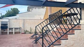 Una escalera con barandilla metálica que conduce a un espacio al aire libre techado.