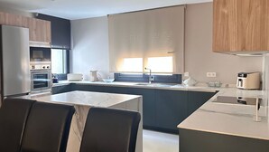 Eine moderne Küche mit Kochinsel, Einbauofen und Essbereich mit Marmortisch und Stühlen.