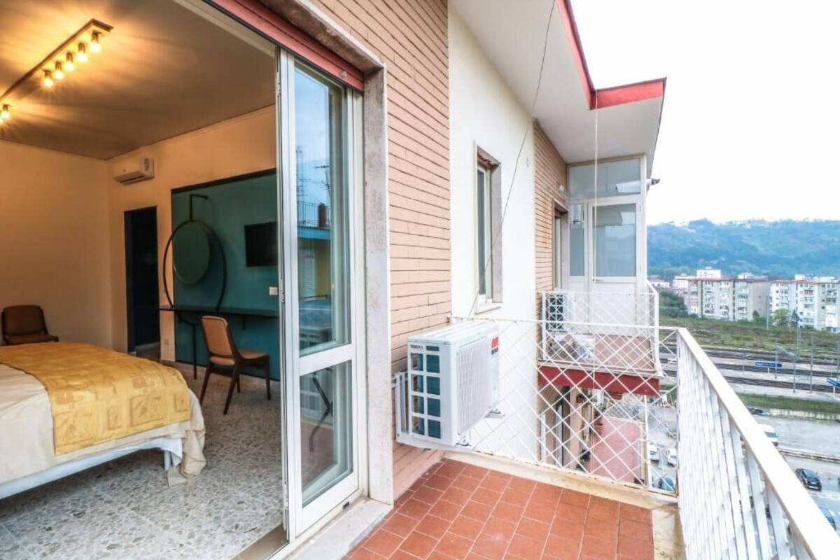 A balcony with a bed, a desk, and a chair.